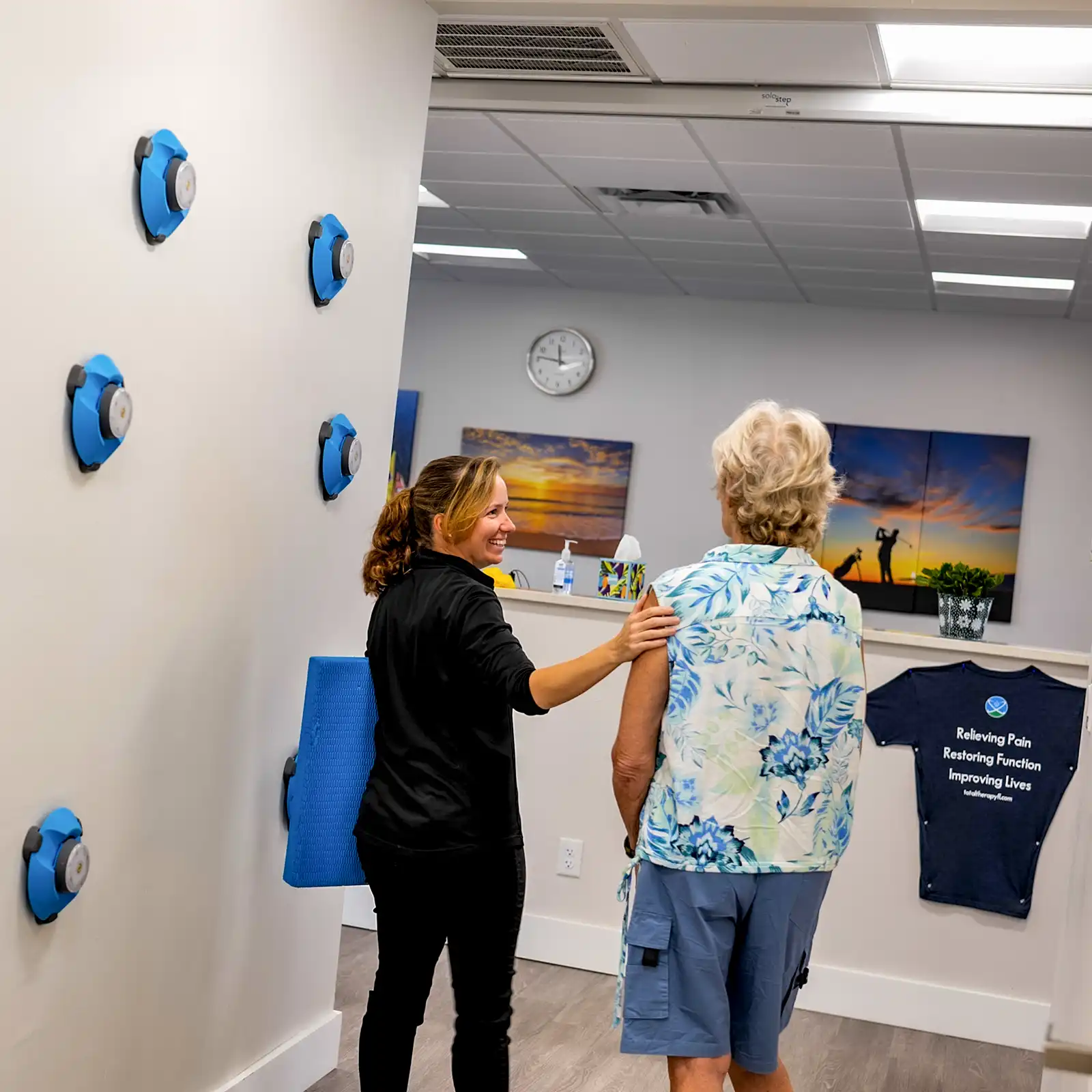 Physical therapy assistant encouraging a patient during rehabilitation at Total Therapy Florida